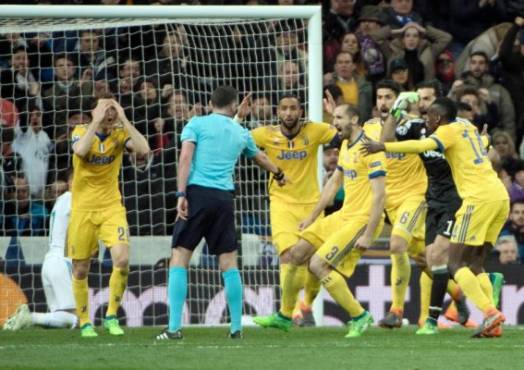 Juventus players protest as English referee Michael Oliver (2L) signals a penalty kick during the UEFA Champions League quarter-final second leg football match between Real Madrid CF and Juventus FC at the Santiago Bernabeu stadium in Madrid on April 11, 2018. / AFP PHOTO / CURTO DE LA TORRE