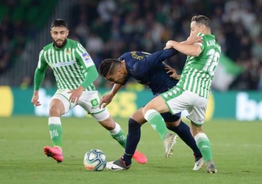 Real Betis' Mexican midfielder Andres Guardado (R) fights for the ball with Real Madrid's Brazilian midfielder Casemiro (C) during the Spanish league football match between Real Betis and Real Madrid CF at the Benito Villamarin stadium in Seville on March 8, 2020. (Photo by CRISTINA QUICLER / AFP)
