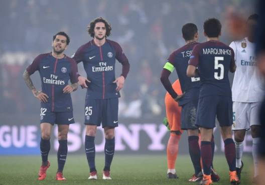 Paris Saint-Germain's Brazilian defender Daniel Alves (L) and Paris Saint-Germain's French midfielder Adrien Rabiot react react after losing the UEFA Champions League round of 16 second leg football match between Paris Saint-Germain (PSG) and Real Madrid on March 6, 2018, at the Parc des Princes stadium in Paris. / AFP PHOTO / FRANCK FIFE