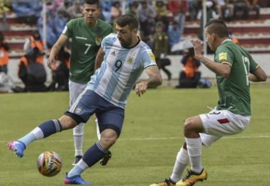 Argentina's Lucas Pratto (C) vies for the ball with Bolivia's Ruben Cordano (R) during their 2018 FIFA World Cup qualifier football match in La Paz, on March 28, 2017. / AFP PHOTO / AIZAR RALDES