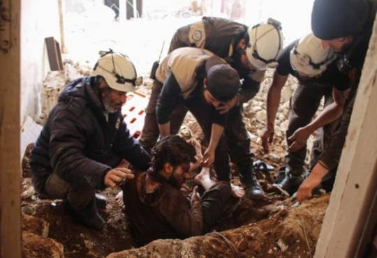 Members of the Syrian civil defence volunteers, also known as the White Helmets, remove a victim from the rubble of his house on April 8, 2017, following a reported air strike by government forces on a rebel-held area in the southern Syrian city of Daraa. / AFP PHOTO / Mohamad ABAZEED