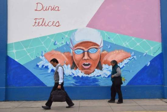 Locals walk past murals on the walls of a municipal stadium in Lima on July 17, 2019, depicting national sportsmen and women participating in the Lima-2019 Pan-American Games that will take place from July 26 to August 11. - Over 600 Peruvian athletes are expected to participate in the Lima 2019 Pan American Games. (Photo by Cristobal BOURONCLE and CRIS BOURONCLE / AFP)