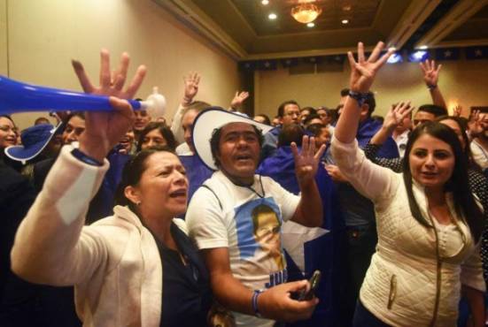 Supporters of Honduran President and presidential candidate Juan Orlando Hernandez are in a festive mood in Tegucigalpa after the general election on November 26, 2017. Honduras' six million voters are to cast ballots in a controversial election Sunday in which President Juan Orlando Hernandez is seeking a second mandate despite a constitutional one-term limit. This small country is at the heart of Central America's 'triangle of death,' an area plagued by gangs and poverty. / AFP PHOTO / RODRIGO ARANGUA