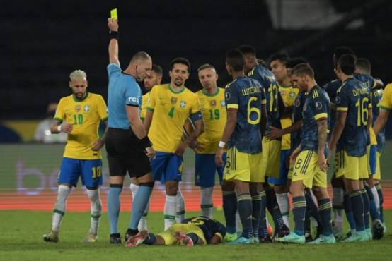 Argentine referee Nestor Pitana shows a yellow card to Brazil's Neymar (L) during the Conmebol Copa America 2021 football tournament group phase match between Brazil and Colombia at the Nilton Santos Stadium in Rio de Janeiro, Brazil, on June 23, 2021. (Photo by CARL DE SOUZA / AFP)
