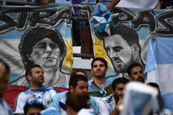 Argentina fans sit in front of banners with the images of Argentina's forward Lionel Messi (R) and former Argentina football player Diego Maradona before the Russia 2018 World Cup round of 16 football match between France and Argentina at the Kazan Arena in Kazan on June 30, 2018. / AFP PHOTO / Jewel SAMAD / RESTRICTED TO EDITORIAL USE - NO MOBILE PUSH ALERTS/DOWNLOADS