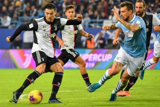 Juventus' Portuguese forward Cristiano Ronaldo (L) attempts a shot as he is marked by Lazio's Italian defender Francesco Acerbi (R) during the Supercoppa Italiana final football match between Juventus and Lazio at the King Saud University Stadium in the Saudi capital Riyadh on December 22, 2019. (Photo by GIUSEPPE CACACE / AFP)