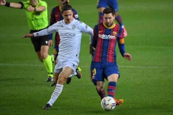 Barcelona's Argentinian forward Lionel Messi challenges Huesca's Spanish midfielder Jaime Seoane (L) during the Spanish League football match between Barcelona and SD Huesca at the Camp Nou stadium in Barcelona on March 15, 2021. (Photo by LLUIS GENE / AFP)