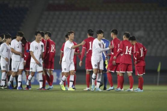 This handout photo taken on October 15, 2019 by the Korea Football Association (KFA) shows South Korea (white) and North Korea (red) players shaking hands after the World Cup 2022 Qualifying Asian zone Group H football match between South Korea and North Korea at Kim Il Sung Stadium in Pyongyang. - North and South Korea drew 0-0 in a historic but surreal World Cup qualifier on October 15, played in front of an empty stadium and almost completely blocked off from the outside world. (Photo by handout / Korea Football Association / AFP) / - South Korea OUT / REPUBLIC OF KOREA OUT RESTRICTED TO EDITORIAL USE - MANDATORY CREDIT 'AFP PHOTO / KFA' - NO MARKETING NO ADVERTISING CAMPAIGNS - DISTRIBUTED AS A SERVICE TO CLIENTS == NO ARCHIVE