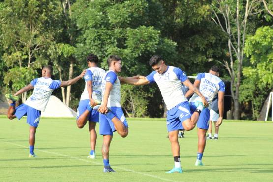 Bryan Moya mientras estira con el volante Luis Palma, del Aris de Grecia.