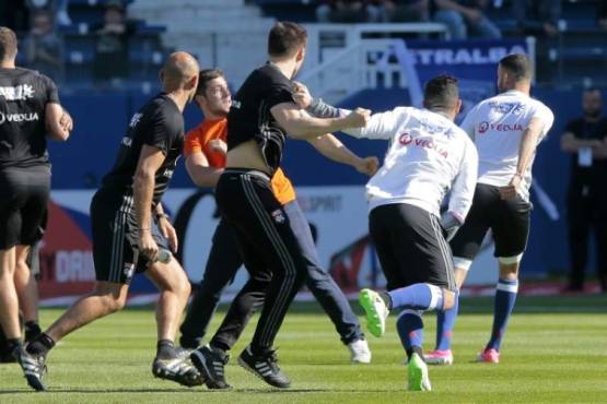 A Bastia's supporter fights with Lyon's player during their the warm up prior to the French L1 Football match between Bastia (SCB) and Lyon (OL) on April 16, 2017, at the Armand Cesari stadium, in Bastia, on the French Mediterranean island of Corsica. / AFP PHOTO / PASCAL POCHARD-CASABIANCA