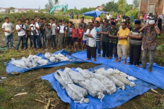 Indonesian villagers perform funeral prayers on the discovered remains of the 2004 tsunami and earthquake victims in Kajhu, Aceh province on December 24, 2018. - The remains of some thirteen 2004 tsunami and earthquake victims were discovered near a construction for a road in Kajhu. Aceh province experienced a 9.1-magnitude earthquake followed by a tsunami on December 26, 2004, killing more than 170,000 in Indonesia alone. (Photo by CHAIDEER MAHYUDDIN / AFP)