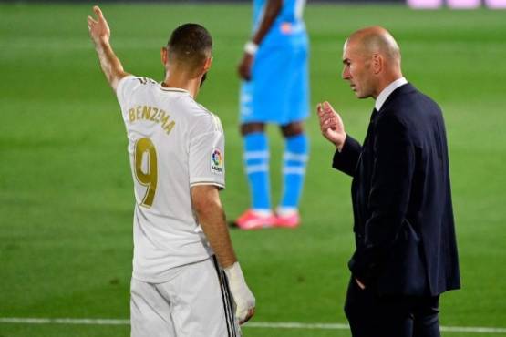 Real Madrid's French coach Zinedine Zidane (R) talks with Real Madrid's French forward Karim Benzema during the Spanish league football match between Real Madrid CF and Valencia CF at the Alfredo di Stefano stadium in Valdebebas, on the outskirts of Madrid, on June 18, 2020. (Photo by JAVIER SORIANO / AFP)