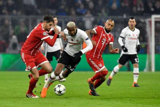 Besiktas' Brazilian midfielder Talisca (C) fights for the ball with Bayern Munich's Chilean midfielder Arturo Vidal during the UEFA Champions League round of sixteen first leg football match Bayern Munich vs Besiktas Istanbul on February 20, 2018 in Munich, southern Germany. / AFP PHOTO / Thomas KIENZLE