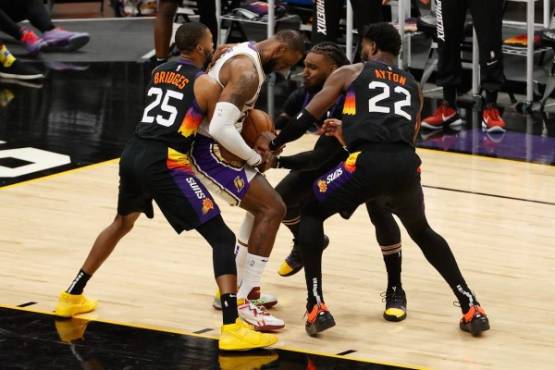 PHOENIX, ARIZONA - MAY 23: LeBron James #23 of the Los Angeles Lakers attempts to control the ball from Mikal Bridges #25, Jae Crowder #99 and Deandre Ayton #22 of the Phoenix Suns during the second half of Game One of the Western Conference first-round playoff series at Phoenix Suns Arena on May 23, 2021 in Phoenix, Arizona. The Suns defeated the Lakers 99-90. NOTE TO USER: User expressly acknowledges and agrees that, by downloading and or using this photograph, User is consenting to the terms and conditions of the Getty Images License Agreement. Christian Petersen/Getty Images/AFP (Photo by Christian Petersen / GETTY IMAGES NORTH AMERICA / Getty Images via AFP)