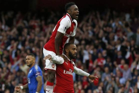 Arsenal's French striker Alexandre Lacazette celebrates with Arsenal's English striker Danny Welbeck (up) after scoring the opening goal of the English Premier League football match between Arsenal and Leicester City at the Emirates Stadium in London on August 11, 2017. / AFP PHOTO / Ian KINGTON / RESTRICTED TO EDITORIAL USE. No use with unauthorized audio, video, data, fixture lists, club/league logos or 'live' services. Online in-match use limited to 75 images, no video emulation. No use in betting, games or single club/league/player publications. /