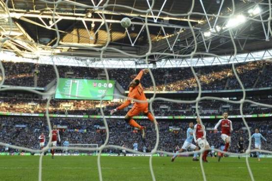 Manchester City's Argentinian striker Sergio Aguero (centre right) turns to celebrate as his shot loops over Arsenal's Colombian goalkeeper David Ospina for their opening goal during the English League Cup final football match between Manchester City and Arsenal at Wembley stadium in north London on February 25, 2018. / AFP PHOTO / Glyn KIRK / RESTRICTED TO EDITORIAL USE. No use with unauthorized audio, video, data, fixture lists, club/league logos or 'live' services. Online in-match use limited to 75 images, no video emulation. No use in betting, games or single club/league/player publications. /