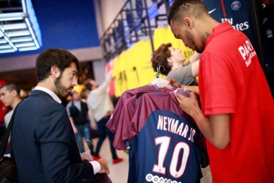 A customer buys a Paris-Saint-Germain Neymar's number 10 jersey at the Paris-Saint-Germain (PSG) football club store on the Champs Elysees avenue in Paris on August 4, 2017.Paris Saint-Germain have signed Brazilian forward Neymar from Barcelona for a world-record transfer fee of 222 million euros (around $264 million), more than doubling the previous record. / AFP PHOTO / BENJAMIN CREMEL