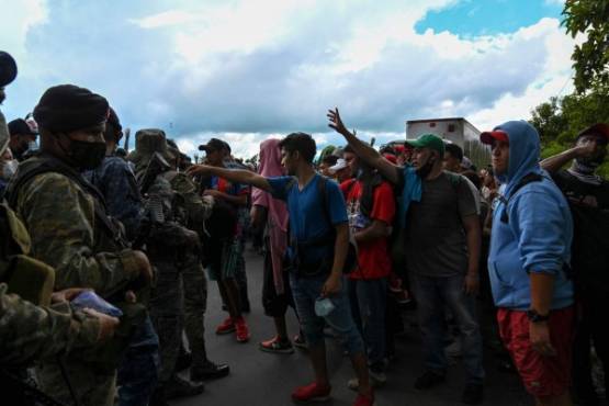 Honduran migrants, part of a caravan heading to the US, reach for water given to them by members of the Guatemalan Army, in Entre Rios, Guatemala, after crossing the border from Honduras, on October 1, 2020. - A new caravan, of at least 5,000 people, left San Pedro Sula on Wednesday midnight in search of the American dream amid the new coronavirus pandemic, which has left over 2,300 dead in Honduras so far. (Photo by Johan ORDONEZ / AFP)