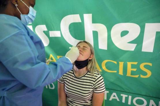 A healthcare worker conducts a polymerase chain reaction (PCR) Covid-19 test on a traveller at OR Tambo International Airport in Johannesburg on November 27, 2021, after several countries banned flights from South Africa following the discovery of a new Covid-19 variant Omicron. - A flurry of countries around the world have banned ban flights from southern Africa following the discovery of the variant, including the United States, Canada, Australia,Thailand, Brazil and several European countries. The main countries targeted by the shutdown include South Africa, Botswana, eSwatini (Swaziland), Lesotho, Namibia, Zambia, Mozambique, Malawi and Zimbabwe. (Photo by Phill Magakoe / AFP)