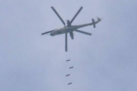 A Syrian army helicopter drops bombs on a rebel-held area in the southern Syrian city of Daraa, on April 8, 2017. / AFP PHOTO / Mohamad ABAZEED