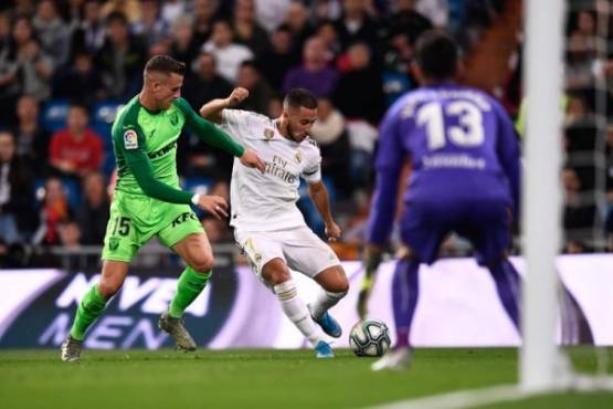 Real Madrid's Belgian forward Eden Hazard (C) vies with Leganes' Spanish defender Rodrigo Tarin (L) during the Spanish league football match between Real Madrid CF and Club Deportivo Leganes SAD at the Santiago Bernabeu stadium in Madrid on October 30, 2019. (Photo by OSCAR DEL POZO / AFP)