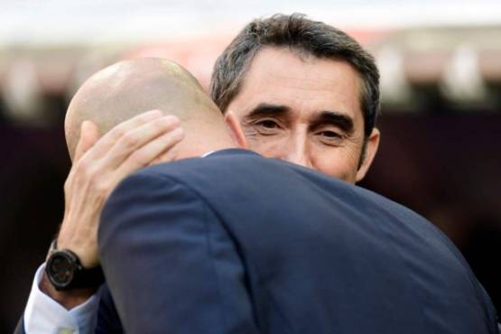 Barcelona's Spanish coach Ernesto Valverde (R) hugs Real Madrid's French coach Zinedine Zidane before the Spanish League 'Clasico' football match Real Madrid CF vs FC Barcelona at the Santiago Bernabeu stadium in Madrid on December 23, 2017. / AFP PHOTO / JAVIER SORIANO