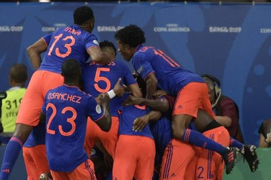 Colombian players celebrate after teammate Roger Martinez (covered) scored against Argentina during their Copa America football tournament group match at the Fonte Nova Arena in Salvador, Brazil, on June 15, 2019. (Photo by Juan MABROMATA / AFP)