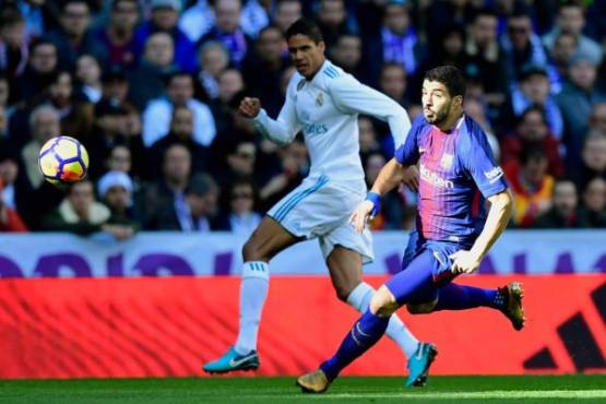 Real Madrid's French defender Raphael Varane (L) vies for the ball with Barcelona's Uruguayan forward Luis Suarez during the Spanish League 'Clasico' football match Real Madrid CF vs FC Barcelona at the Santiago Bernabeu stadium in Madrid on December 23, 2017. / AFP PHOTO / JAVIER SORIANO