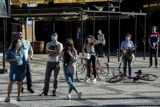 People wearing the face masks watch the astronomical clock chime at the Old Town Square on April 8, 2020, in Prague where most activities slowed down or came to a halt due to the spread of the novel coronavirus COVID-19. (Photo by Michal Cizek / AFP)