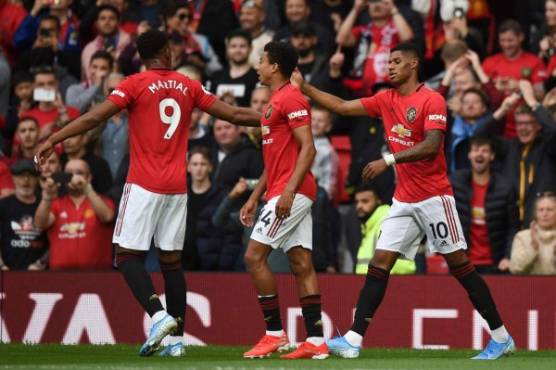 Manchester United's English striker Marcus Rashford (R) celebrates with teammates after scoring the opening goal from the penalty spot during the English Premier League football match between Manchester United and Chelsea at Old Trafford in Manchester, north west England, on August 11, 2019. (Photo by Oli SCARFF / AFP) / RESTRICTED TO EDITORIAL USE. No use with unauthorized audio, video, data, fixture lists, club/league logos or 'live' services. Online in-match use limited to 120 images. An additional 40 images may be used in extra time. No video emulation. Social media in-match use limited to 120 images. An additional 40 images may be used in extra time. No use in betting publications, games or single club/league/player publications. /