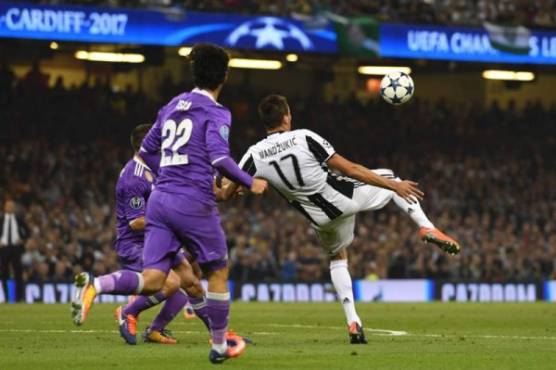 Juventus' Croatian striker Mario Mandzukic shoots to score their first goal during the UEFA Champions League final football match between Juventus and Real Madrid at The Principality Stadium in Cardiff, south Wales, on June 3, 2017. / AFP PHOTO / Glyn KIRK
