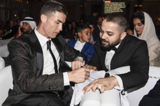 Juventus' Portuguese forward Cristiano Ronaldo signs an autograph for a fan during the 10th edition of the Dubai Globe Soccer Awards on January 3, 2019 in Dubai. (Photo by Fabio FERRARI / La Presse / AFP) / Italy OUT - China OUT