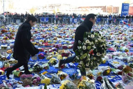 Aiyawatt Srivaddhanaprabha (R) and Aimon Srivaddhanaprabha (L), the son and wife of Leicester City's Thai chairman Vichai Srivaddhanaprabha who died in a helicopter crash at the club's stadium, lay wreathes at the tributes to the victims of the crash at Leicester City Football Club's King Power Stadium in Leicester, eastern England, on October 29, 2018. - Leicester City's chairman Vichai Srivaddhanaprabha was among five people killed when his helicopter crashed and burst into flames in the Premier League side's stadium car park moments after taking off from the pitch, the club said on October 28. A stream of fans already fearing the worst had laid out flowers, football scarves and Buddhist prayers outside the club's King Power stadium after Saturday's accident in tribute to the Thai billionaire boss -- the man they credit for an against-all-odds Premier League victory in 2016 (Photo by Paul ELLIS / AFP)