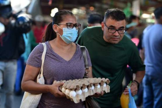 A woman wears a protective face mask to prevent the spread of the new Coronavirus, at the Agriculture Market, in Tegucigalpa, on March 14, 2020. - Honduran government has prohibited citizens from Europe, China, Iran, and South Korea the entrance to the country. (Photo by ORLANDO SIERRA / AFP)