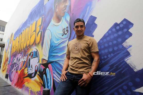 Michael Chirinos posando en las afueras de su negocio que lleva un mural con su figura.