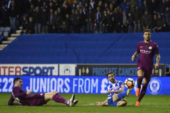 Wigan Athletic's English-born Northern Irish striker Will Grigg (C) scores his team's first goal during the English FA Cup fifth round football match between Wigan Athletic and Manchester City at the DW Stadium in Wigan, northwest England, on February 19, 2018. / AFP PHOTO / Oli SCARFF / RESTRICTED TO EDITORIAL USE. No use with unauthorized audio, video, data, fixture lists, club/league logos or 'live' services. Online in-match use limited to 75 images, no video emulation. No use in betting, games or single club/league/player publications. /