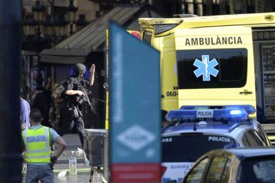 An armed policeman arrives in a cordoned off area after a van ploughed into the crowd, injuring several persons on the Rambla in Barcelona on August 17, 2017.Police in Barcelona said they were dealing with a 'terrorist attack' after a vehicle ploughed into a crowd of pedestrians on the city's famous Las Ramblas boulevard on August 17, 2017. Police were clearing the area after the incident, which has left a number of people injured. / AFP PHOTO / Josep LAGO