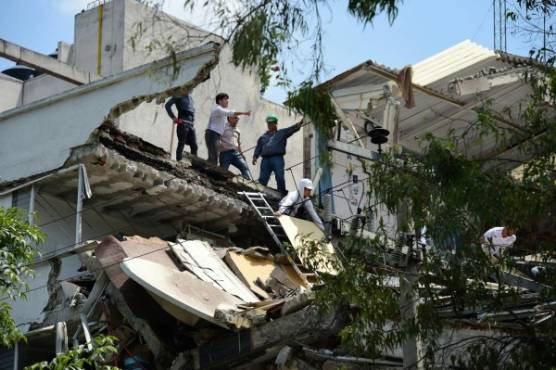 People stand at a building which collapsed after a quake rattled Mexico City on September 19, 2017.A powerful earthquake shook Mexico City on Tuesday, causing panic among the megalopolis' 20 million inhabitants on the 32nd anniversary of a devastating 1985 quake. The US Geological Survey put the quake's magnitude at 7.1 while Mexico's Seismological Institute said it measured 6.8 on its scale. The institute said the quake's epicenter was seven kilometers west of Chiautla de Tapia, in the neighboring state of Puebla. / AFP PHOTO / Ronaldo SCHEMIDT