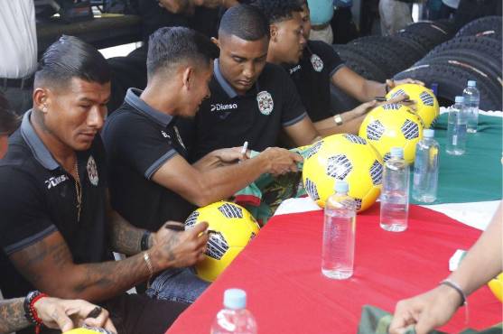 Los jugadores del Marathón firmando balones de fútbol a los aficionados.