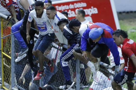 Barristas del Olimpia ingresan a la cancha para después ingresar al sector de preferencia en busca de hinchas del Motagua.
