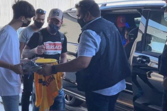 Lionel Messi tras su llegada al aeropuerto firmando una camisa del Barcelona a un fans.
