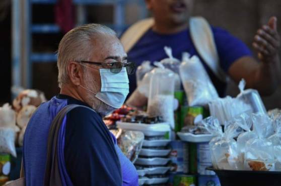 A man wears a protective face mask to prevent the spread of the new Coronavirus, at the Agriculture Market, in Tegucigalpa, on March 14, 2020. - Honduran government has prohibited citizens from Europe, China, Iran, and South Korea the entrance to the country. (Photo by ORLANDO SIERRA / AFP)