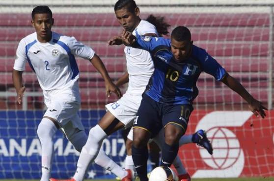 El mediocampista hondureñop Óscar Salas conduce la pelota ante la marca de dos volantes nicaragüenses. Foto AFP