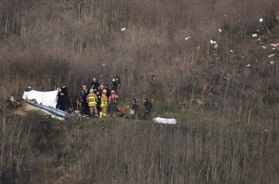 Cuadrillas de emergencias cubren un cadáver, junto al lugar donde se encuentra otro, tras la caída de un helicóptero, en que murió el basquetbolista retirado Kobe Bryant, el domingo 26 de enero de 2020, en Calabasas, California (AP Foto/Mark J. Terrill)