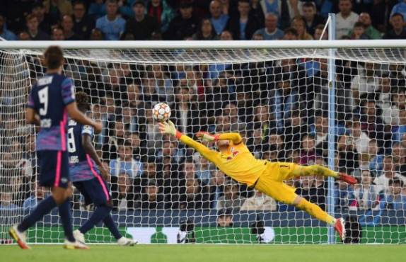 RB Leipzig's Hungarian goalkeeper Peter Gulacsi dives in vain to save a shot from Manchester City's Portuguese defender Joao Cancelo (not seen) for their fifth goal during the UEFA Champions League 1st round Group A football match between Manchester City and RB Leipzig at the Etihad Stadium in Manchester, north west England, on September 15, 2021. (Photo by Oli SCARFF / AFP)