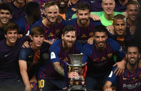 Barcelona's Argentinian forward Lionel Messi (C) carries the cup as they celebrate at the end of the Spanish Super Cup final between Sevilla FC and FC Barcelona at Ibn Batouta Stadium in the Moroccan city of Tangiers on August 12, 2018.Barcelona defeated Sevilla 2-1 to win the Spanish Super Cup. / AFP PHOTO / FADEL SENNA