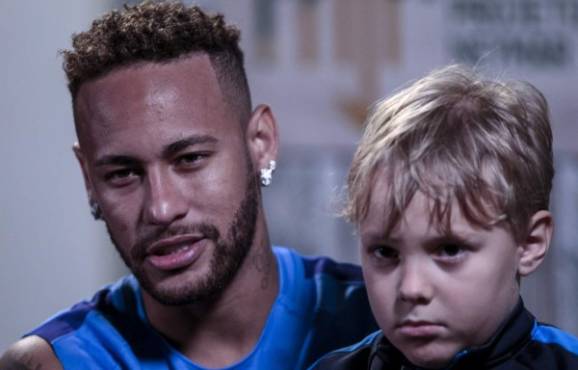 Brazilian football star Neymar, with his son Davi Lucca, offers an interview to AFP on July 21, 2018 at his charity Neymar Junior Project Institute, in Praia Grande, Sao Paulo, Brazil, where he hosted a five-a-side football tournament. / AFP PHOTO / Miguel SCHINCARIOL