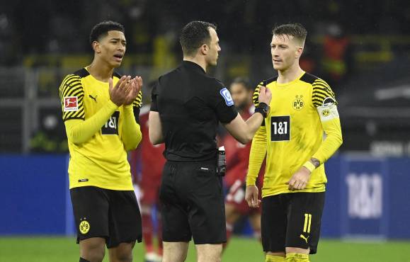 Dortmund's English midfielder Jude Bellingham (L) and Dortmund's German forward Marco Reus (R) discuss with referee Felix Zwayer after a deliberate handball during the German first division Bundesliga football match BVB Borussia Dortmund v FC Bayern Munich in Dortmund, western Germany, on December 3, 2021. (Photo by Ina FASSBENDER / AFP) / DFL REGULATIONS PROHIBIT ANY USE OF PHOTOGRAPHS AS IMAGE SEQUENCES AND/OR QUASI-VIDEO