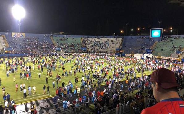 Aficionados de Olimpia y Motagua que invadieron el campo cuando la Policía Nacional lanzó gas lacrimógeno.