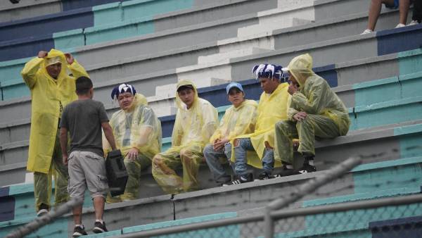 Los aficionados se protegen de la lluvia.